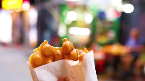 hands reaching for bubble waffles on street