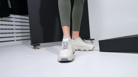 lady in dark green leggings and white trendy sports shoes. close up. studio footwear demonstration.