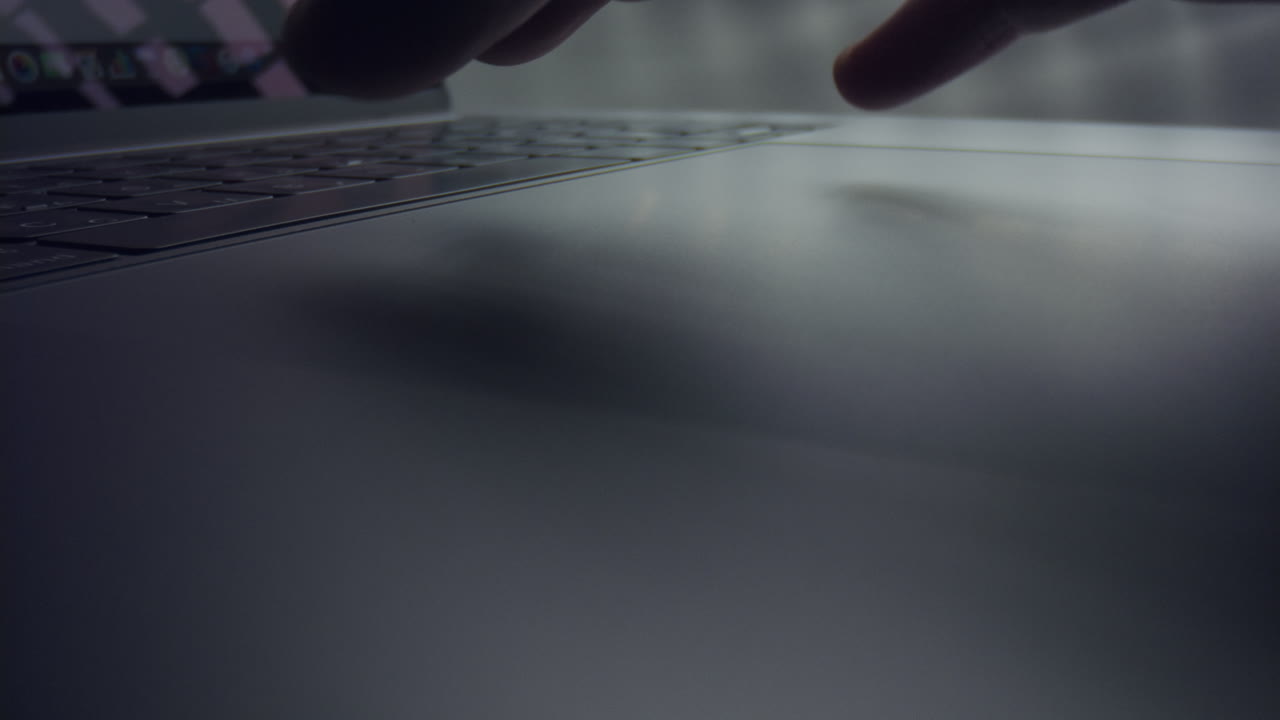 노트북 터치패드를 사용하는 남자의 손. 남자의 손가락이 회색 노트북에서 터치패드를 스크롤합니다.