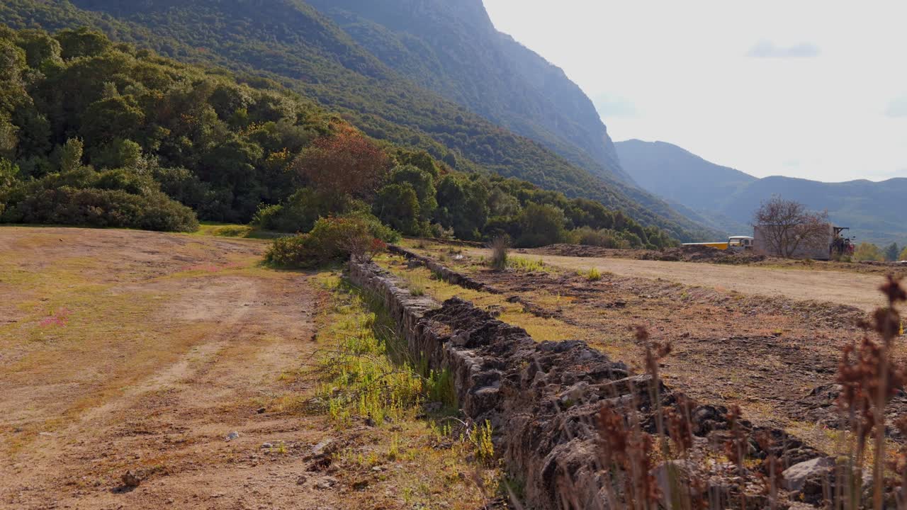 Establihsing reveal of Phocian Wall ruins in Thermopylae, Greece with mountains and dry brush landscape