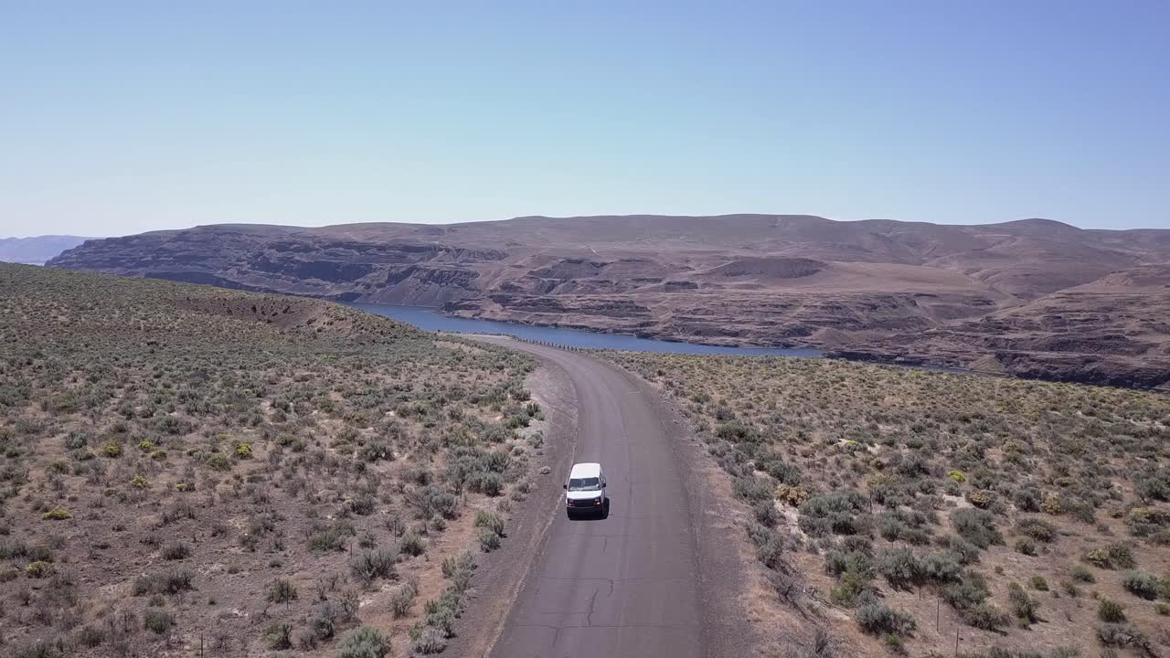 Van drives through scablands sagebrush by Columbia River, aerial view