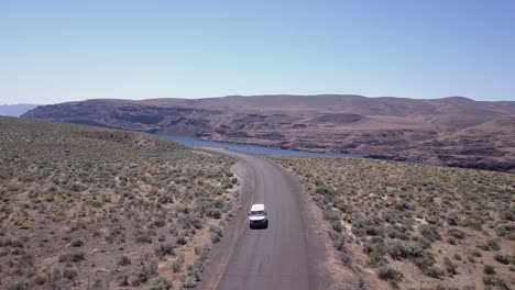 Van-drives-through-scablands-sagebrush-by-Columbia-River,-aerial-view