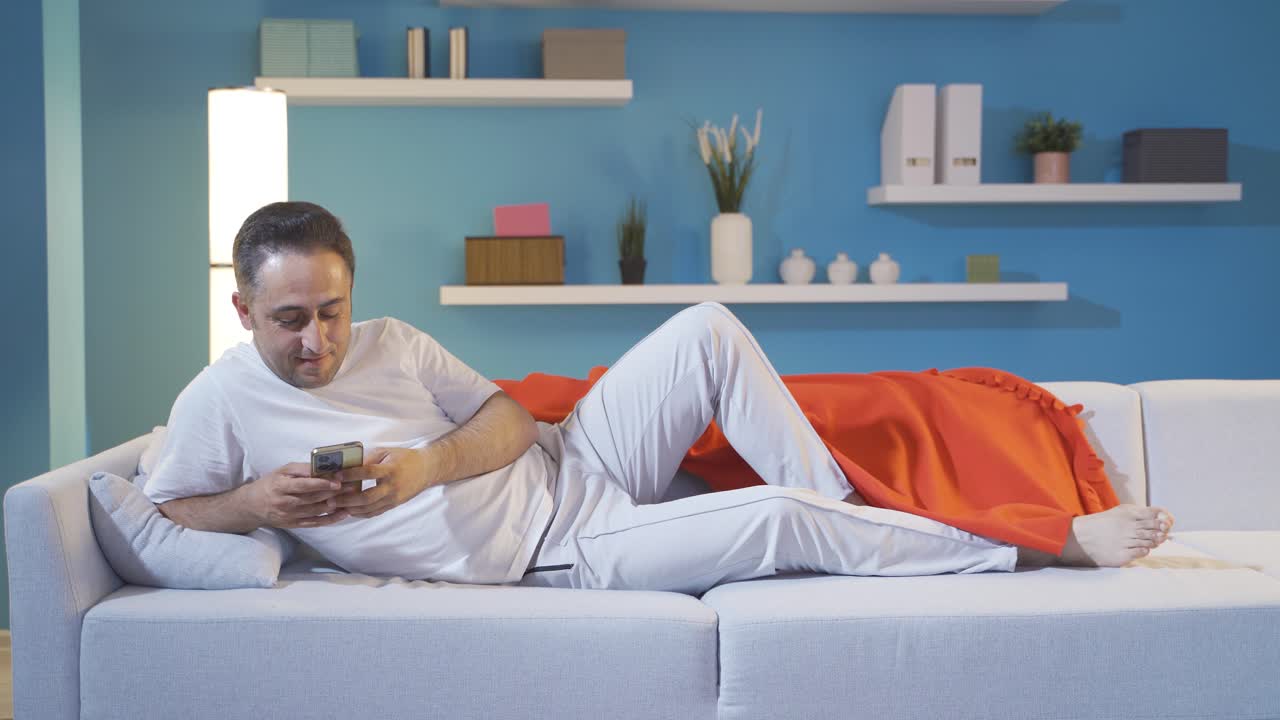 Man Looking At Phone While Lying.