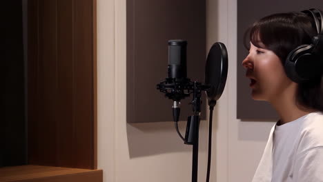 woman in a professional recording studio with a microphone and headphones