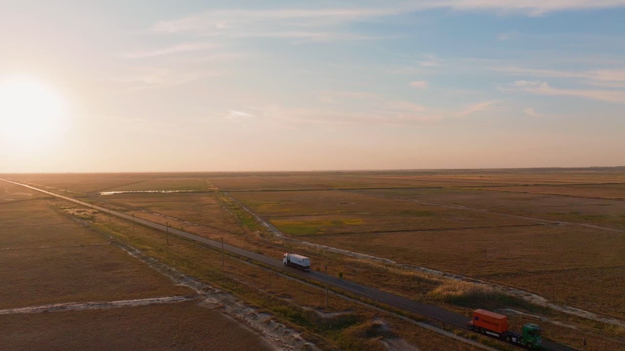 Aerial tracking shot of a transport truck that navigates a straight road, forging ahead towards the radiant embrace of the setting sun, 4K60FPS, cinematic grade