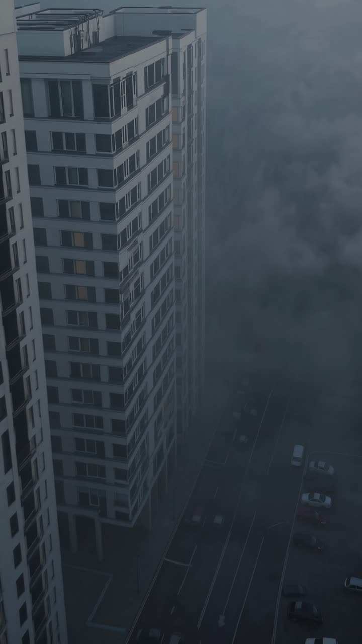 Dense fog enveloping a cluster of urban skyscrapers creates a mysterious and evocative atmosphere, capturing the serene beauty of early morning light and the tranquil cityscape