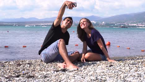 una pareja tomando selfies en la playa.