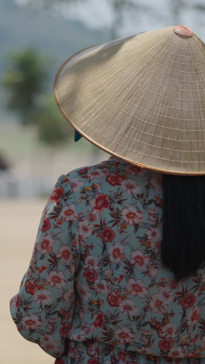Woman wearing asian conical hat and floral shirt