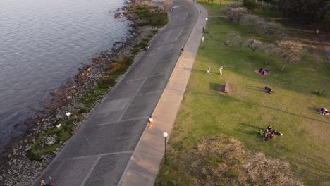 Aerial-track-shot-of-woman-walking-on-waterfront-of-River-Rio-de-la-Plata,Buenos-Aires