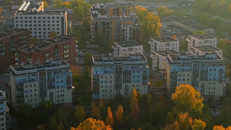 warsaw, poland. aerial view of sunny autumn morning in residential district, soft yellow light above apartment buildings and colorful trees