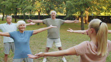 senior people having outdoor workout with female coach