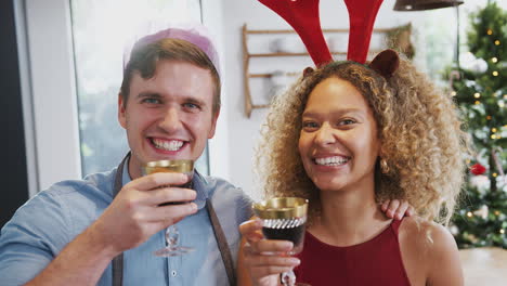 portrait of couple wearing fancy dress antlers and paper hat making a toast on christmas day