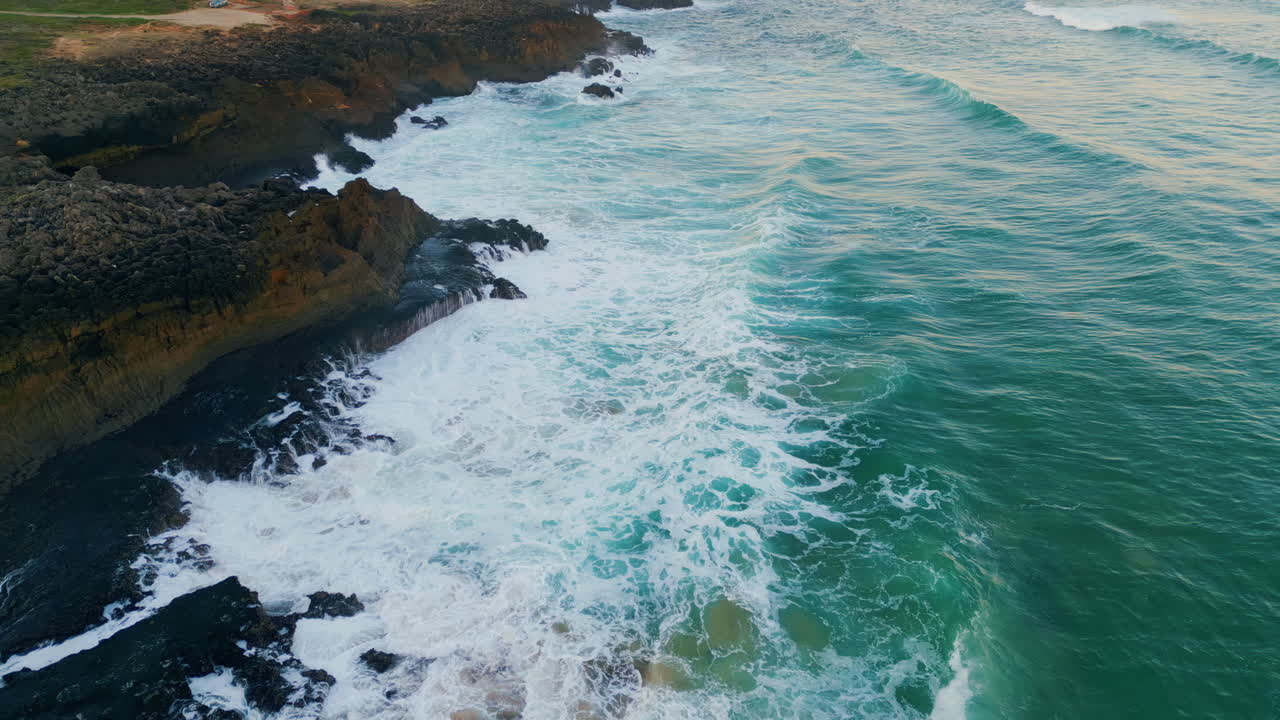 Bellissimo oceano blu schiumoso che si infrange sulla costa rocciosa. Vista aerea di onde impetuose.