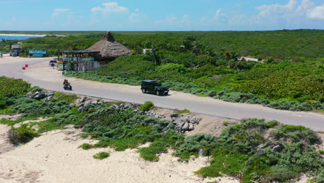 tourists driving scooter on empty coastline road in cozumel mexico, aerial