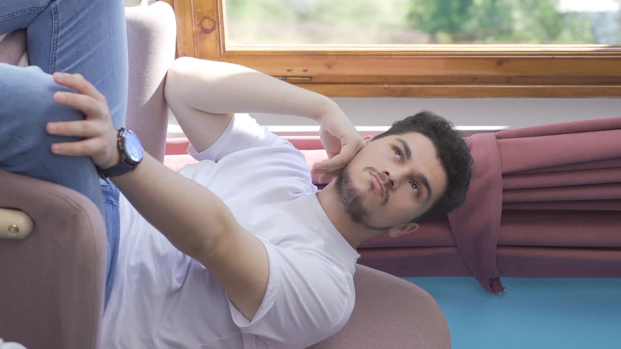 우울한 남자의 수직 비디오. 남자는 창문 밖을 바라보고 있습니다.