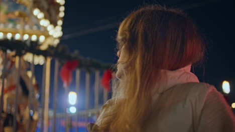 carefree girl looking carousel at christmas fair night closeup. woman enjoying