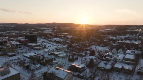 Fayetteville,-AR-Al-Amanecer-Con-Techos-Cubiertos-De-Nieve-En-Invierno,-Cálido-Resplandor-Sobre-La-Ciudad,-Vista-Aérea