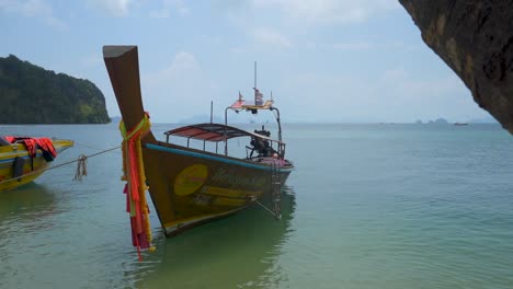 thailand longtail boat anchored on island with calm ocean water and flags in wind