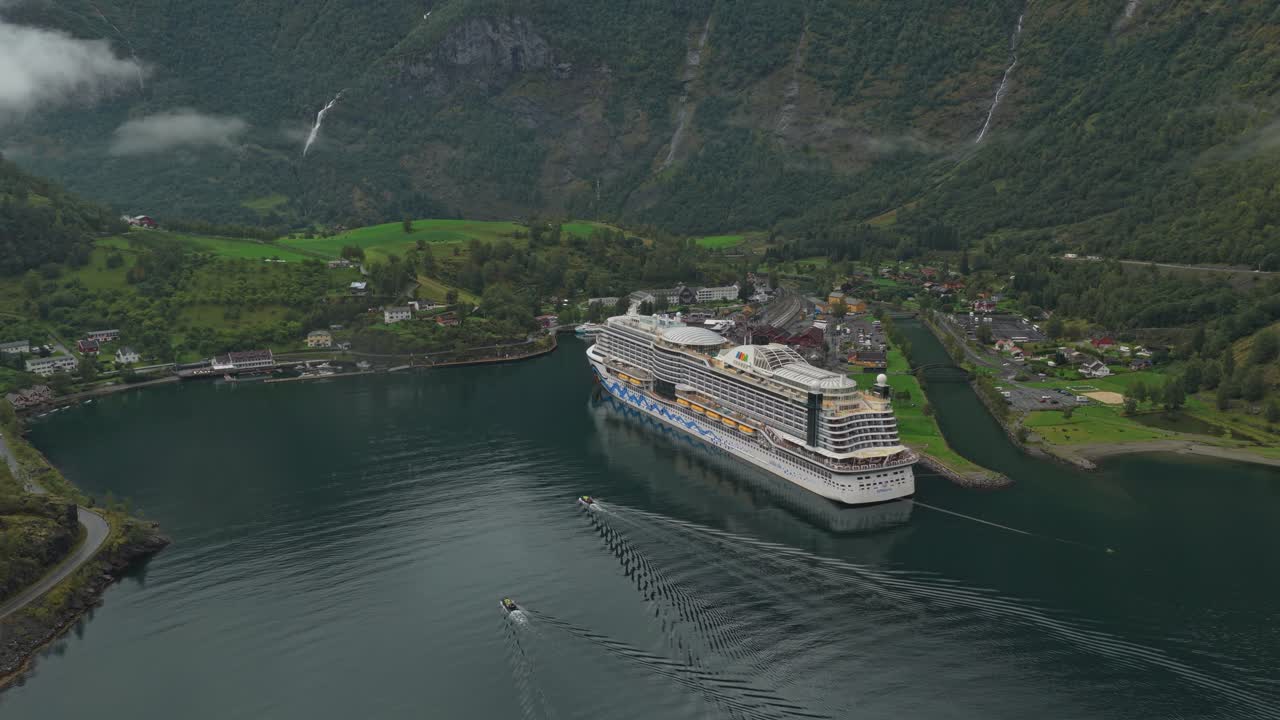 Fugleperspektiv af et krydstogtskib, der ankommer til Flåm på den smalle Aurlandsfjord i Norge