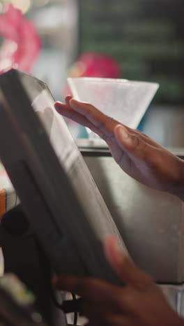 el asistente de la tienda trabaja en la computadora en el mostrador de primer plano. el empleado afroamericano ingresa los datos de la orden en la base del mostrador. el cajero prepara la factura en el escritorio