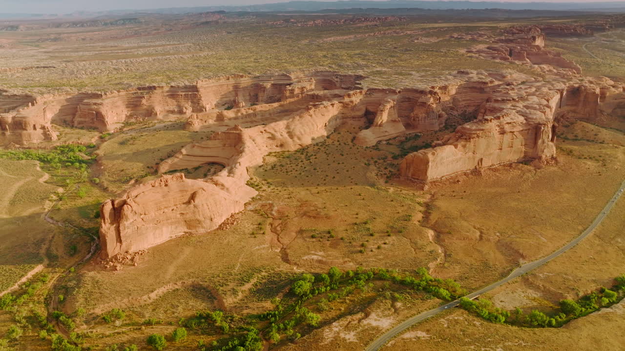 Scenic picture of wonderful canyons of Utah, USA. Drone footage over the rocks. Road crossing the area and greenery rarely growing in desert.