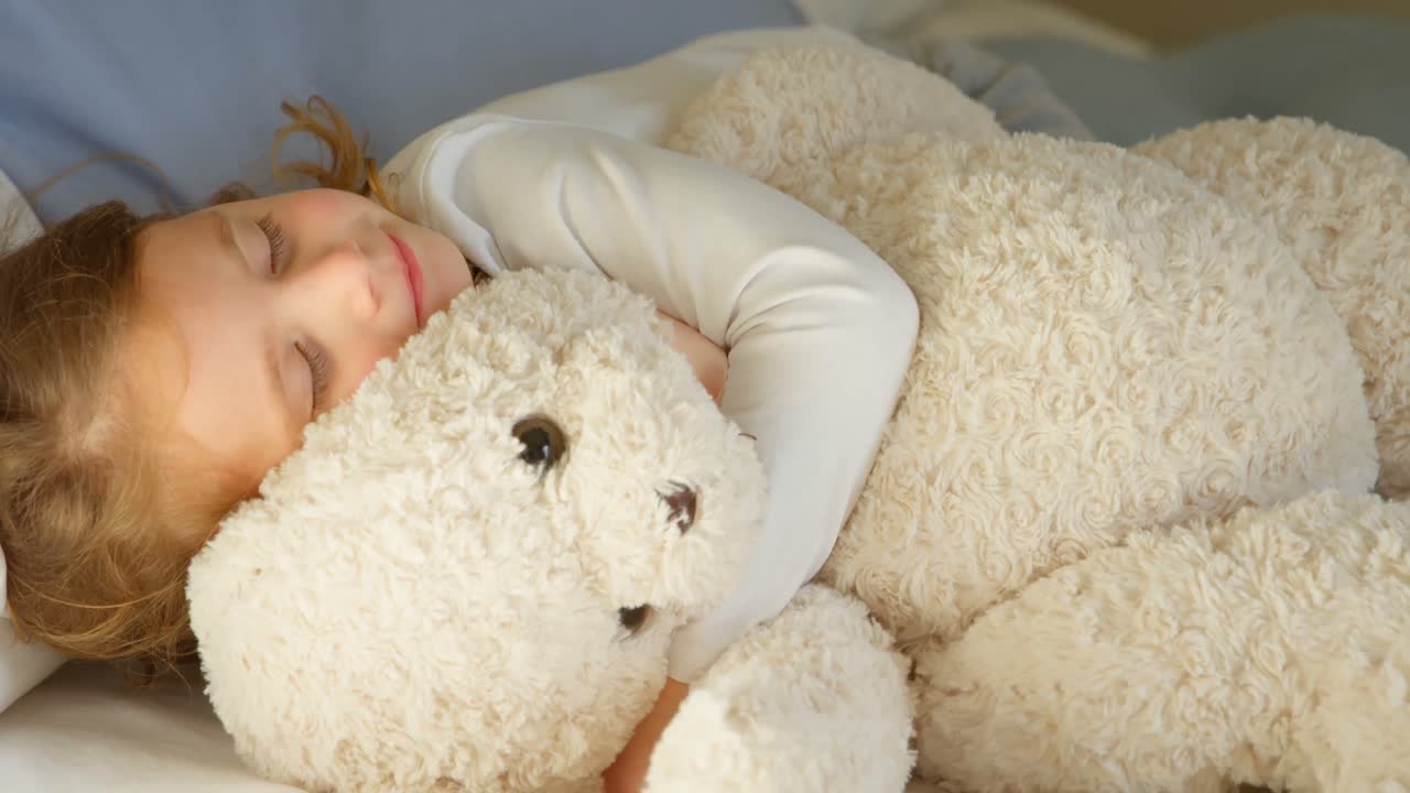 4k 침실에서 테디 베어와 함께 자는 소녀