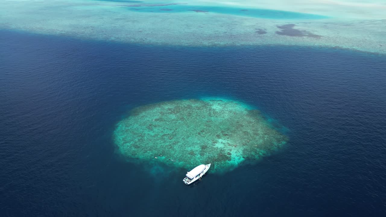 Aerial top down to boat moored in little islet of Maldives in the proximity of Maafushi inhabited islands of Kaafu Atoll