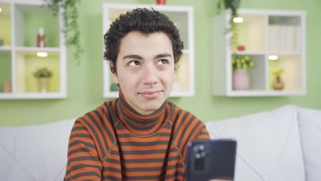 happy boy at home using phone, texting, girlfriend, in good spirits.