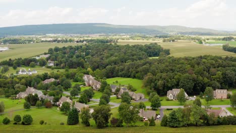 Descending-aerial-of-suburban-American-neighborhood-among-rural-forest-and-fields-in-USA