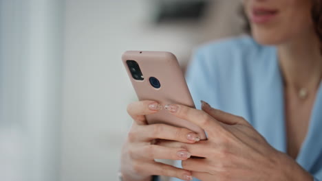 Smiling businesswoman reading phone message in modern workspace closeup