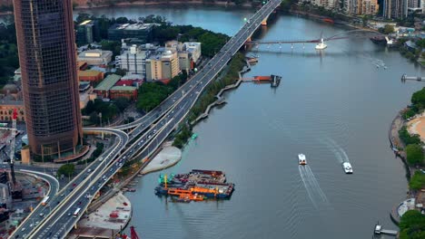 citycat cruising in the brisbane river with traffic on pacific motorway in brisbane, qld, australia