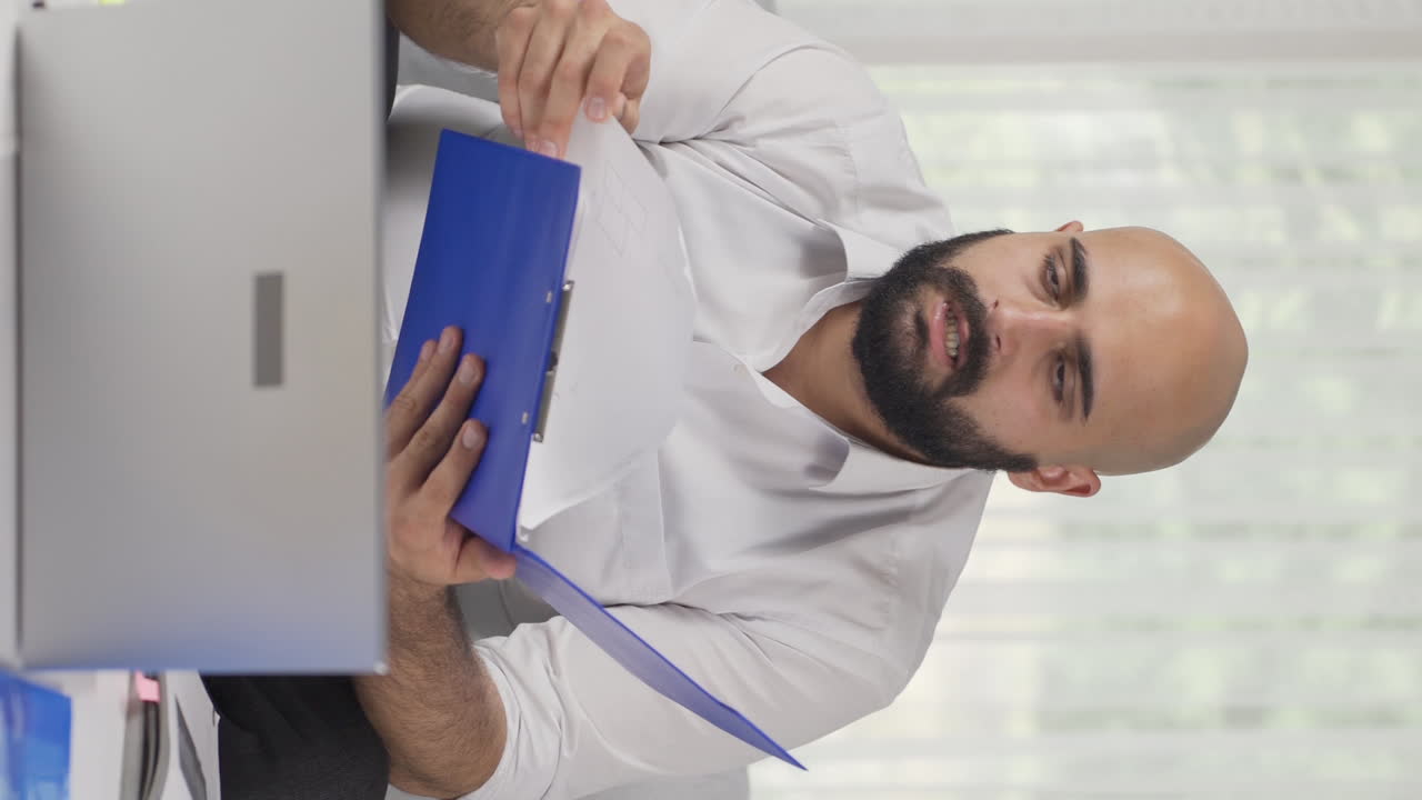 vídeo vertical de un trabajador de oficina en casa mirando el archivo con enojo.