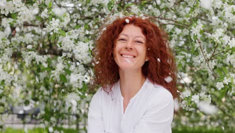 woman smiling under blooming apple trees