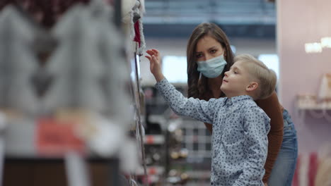 a woman and a boy go shopping and choose christmas trees and toys with decorations for christmas in protective masks