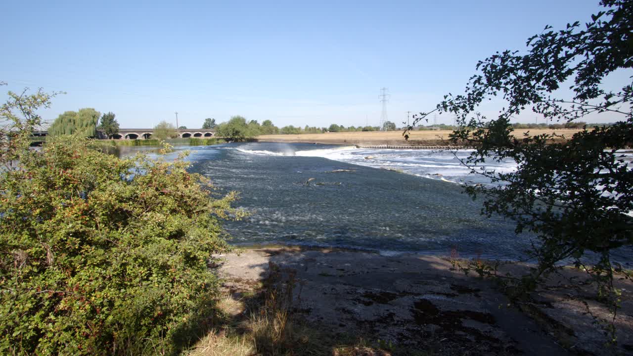 Side shot of water going over the River Trent weir with trees on the side by Ratcliffe on Soar Power station. Wide shot