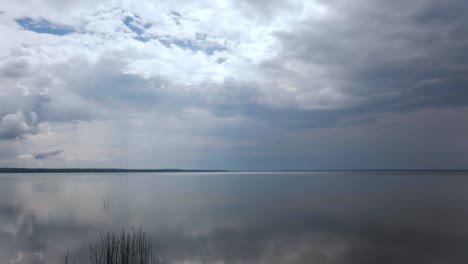 time-lapse of clouds flying over calm lake, wide angle shot