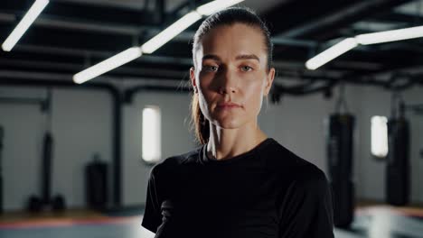 portrait of a confident female athlete standing in a gym with punching bags in the background, showcasing her strength and determination