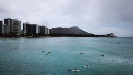 surfers enjoying surfing at waikiki beach in honolulu, hawaii, aerial drone