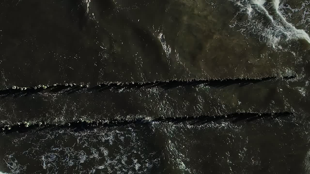 Wellen schlagen bei sonnigem Tageslicht an die Steine der Ostseeküste.