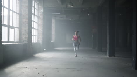 sportswoman training in loft building. female jogger running in gym