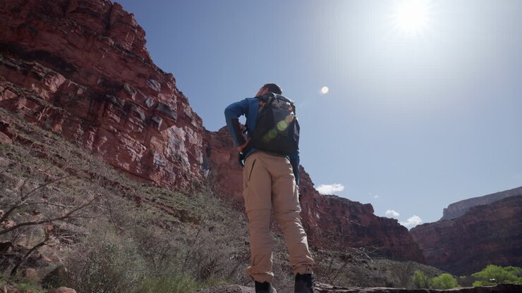 Photographer looks around while holding his camera in the Grand Canyon on a sunny afternoon hike