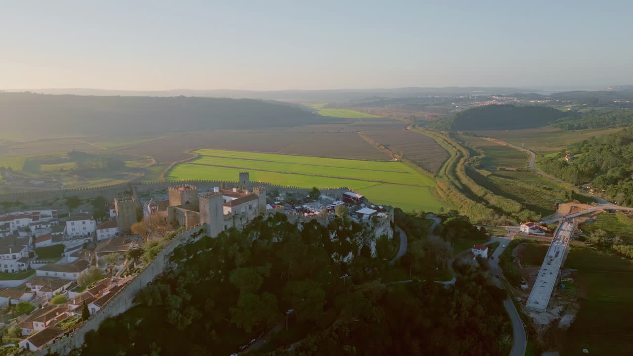 Drone small sunlit town with historic castle in countryside. Scenic landscape