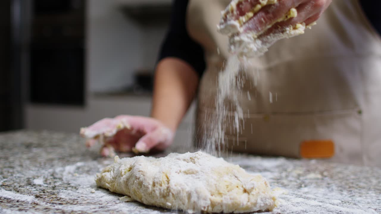 Close-up of a woman dusting flour and kneading dough in slow motion.