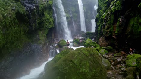 a breathtaking view of a man in the quebrada gata waterfalls in costa rica, showcasing multiple powerful cascades plunging into a rocky riverbed