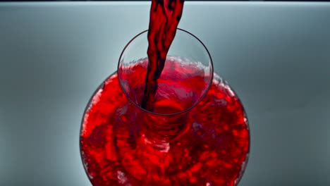primer plano vertiendo un cuenco de vidrio de vino rojo en el interior. decantador de llenado de líquido alcohólico