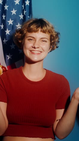 woman celebrating with hot dog in front of american flag