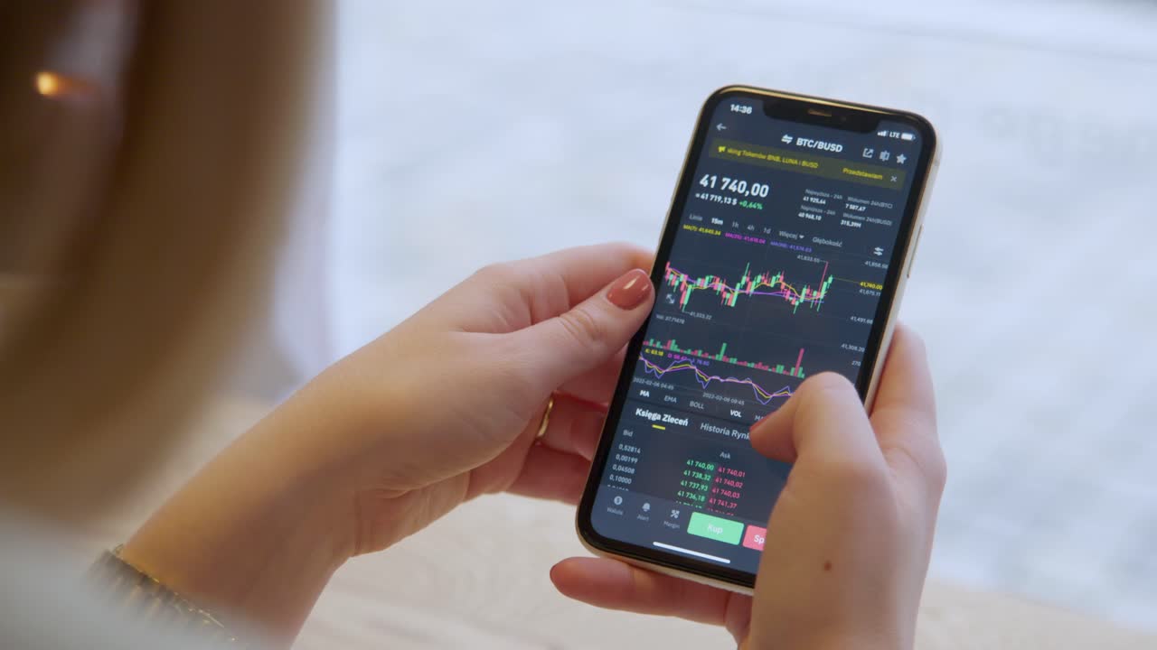 una mujer revisa las tasas de comercio de criptomonedas en su teléfono - toma de primer plano sobre el hombro