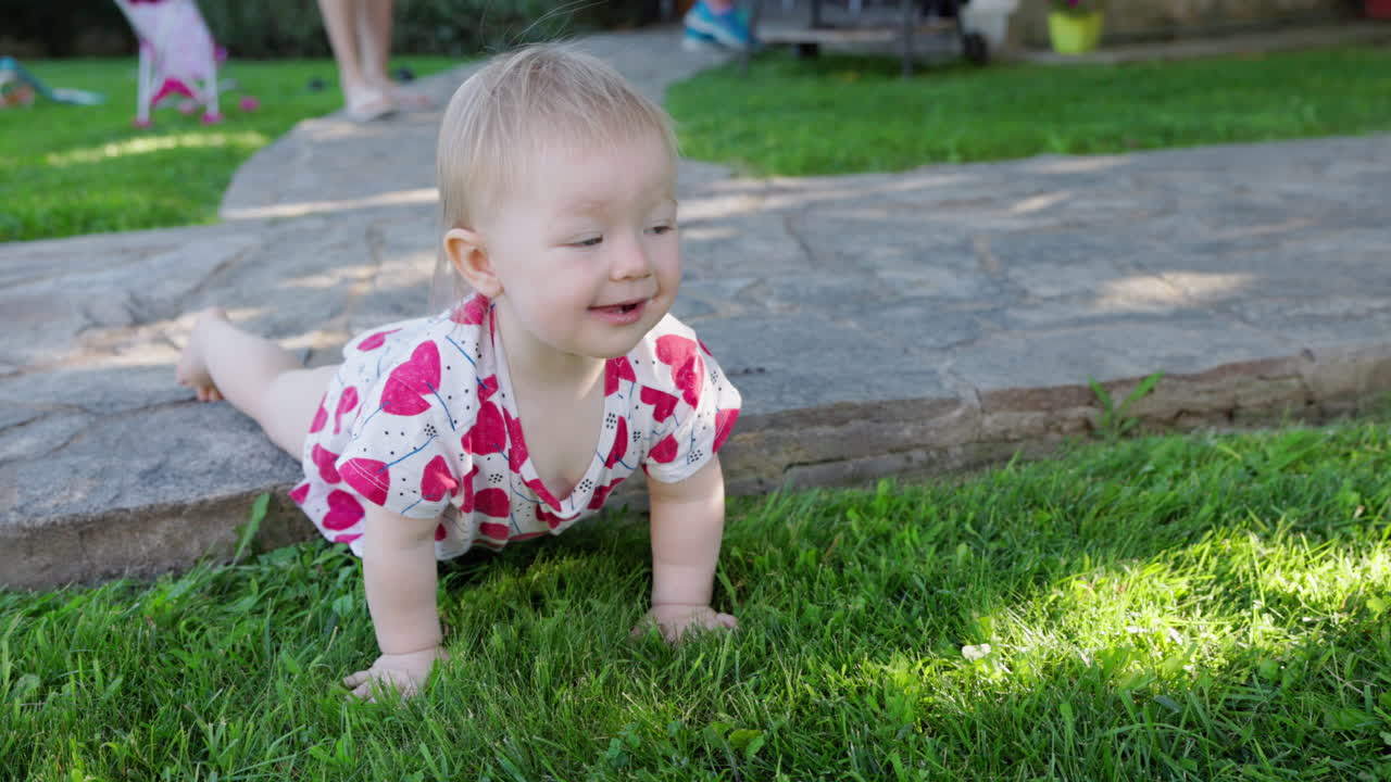 Bambino felice che gattona sull'erba verde in un giardino soleggiato.