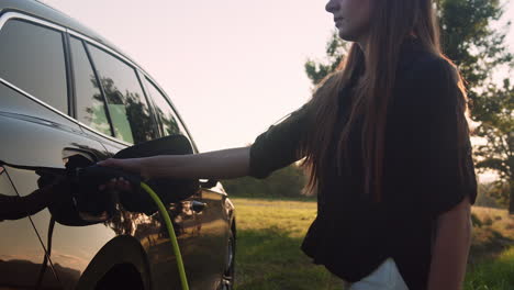 une fille mettant un chargeur dans une voiture et ajustant une application de charge ev sur son mobile