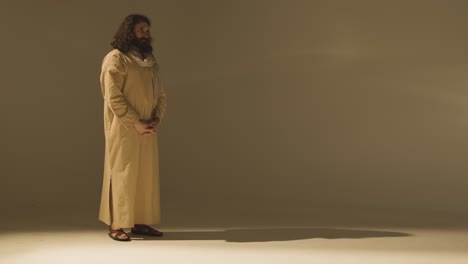 full length studio portrait of man wearing robes and sandals with long hair and beard representing figure of jesus christ